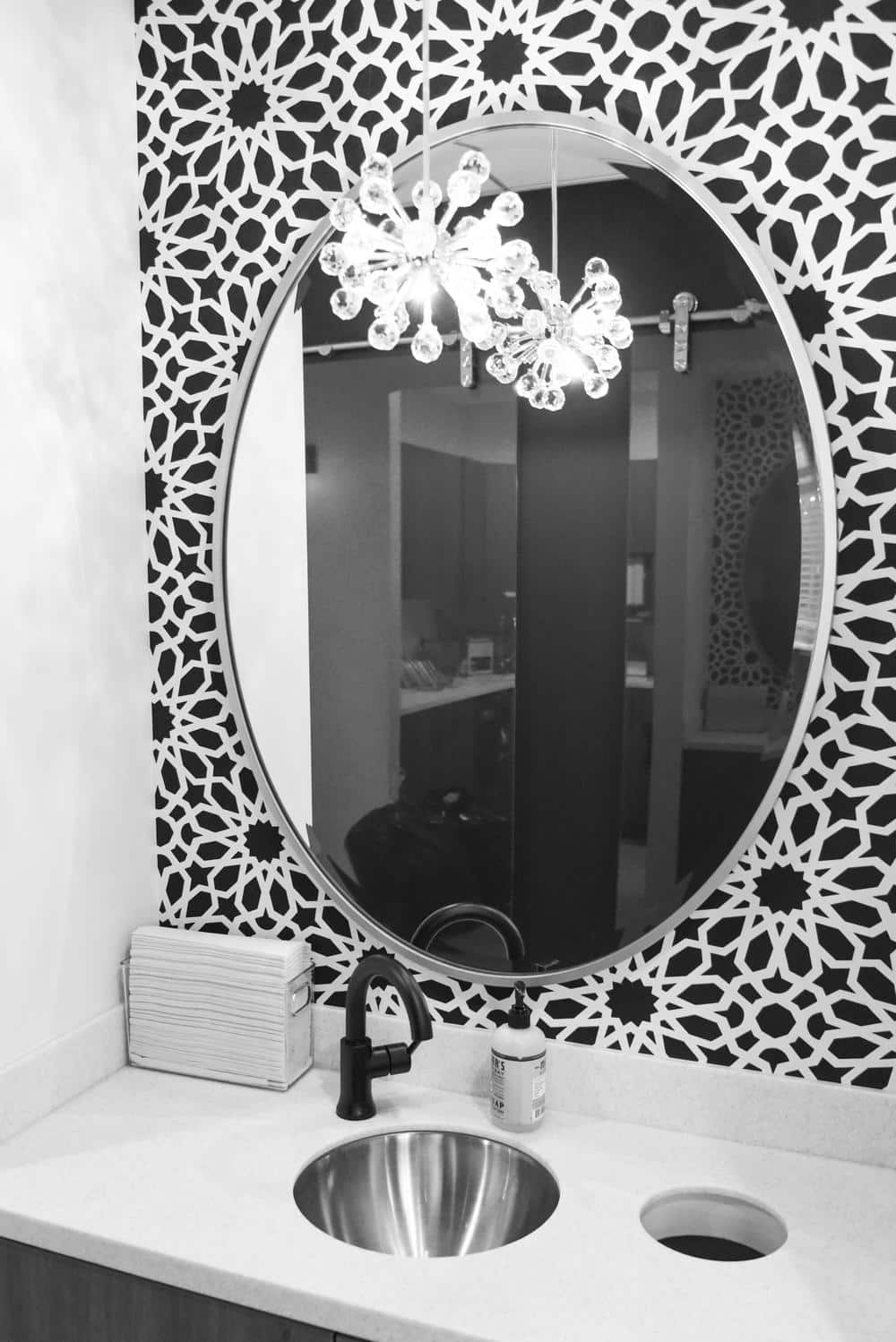 black and white photo of sink and mirror with tiled wall
